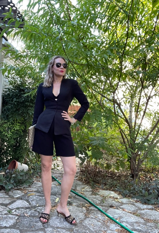 a woman in black Bermuda shorts, bra and blazer with leopard kitten heels and a Gucci clutch