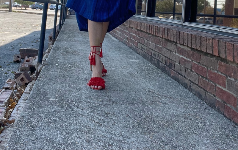 a woman in red lace up heels and a blue striped midi skirt