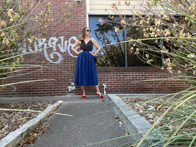 a woman in a blue striped midi skirt, grey strappy top, and red lace up heels 