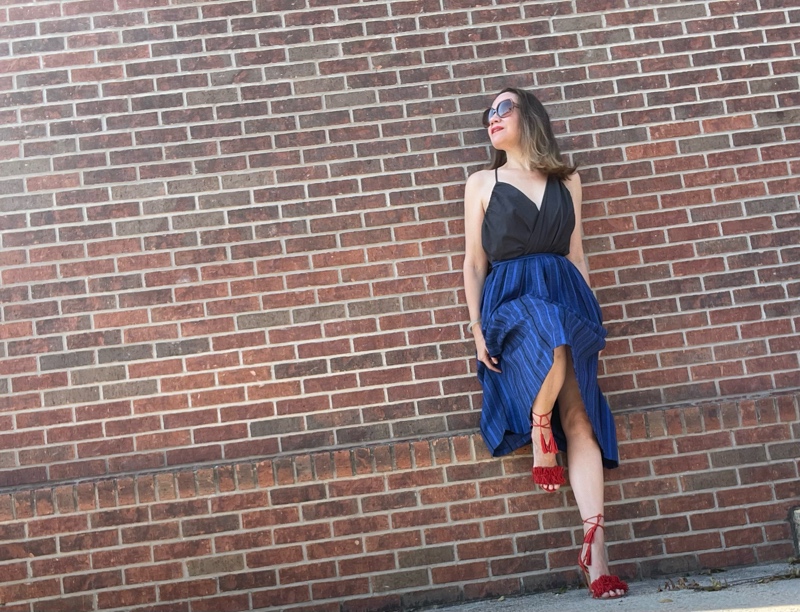 a woman in a blue striped midi skirt with a grey strappy top and red lace up heels