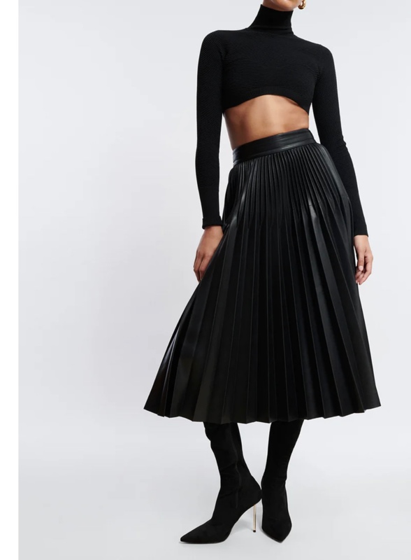 a crop turtleneck with a pleated leather skirt and black boots