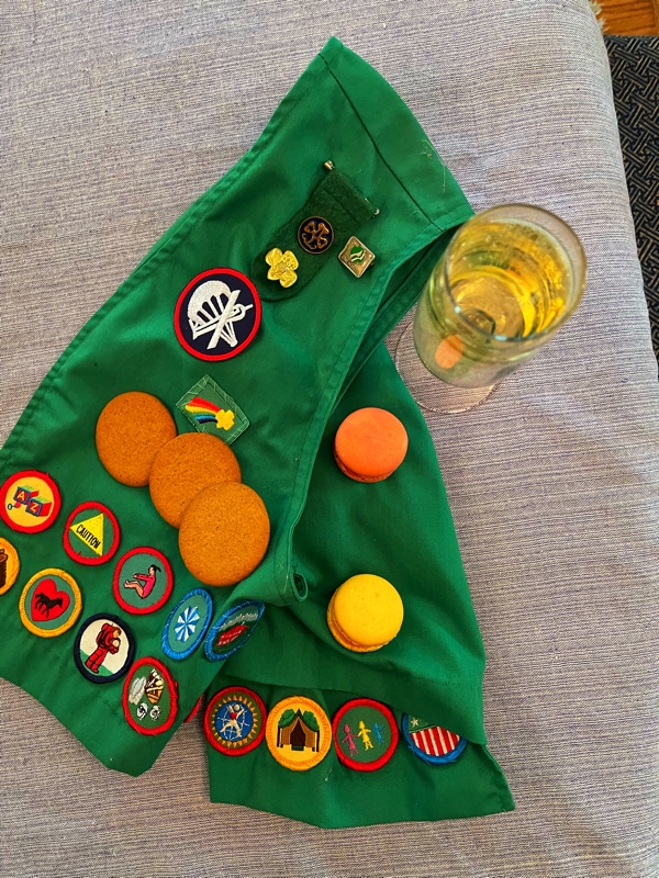 a green vest with patches, various cookies and a glass of champagne