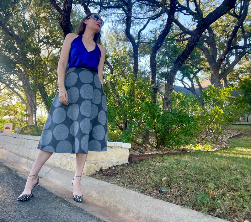 a woman in a blue silk halter top and a grey felt circle skirt with light grey polka dots and houndstooth printed wedges