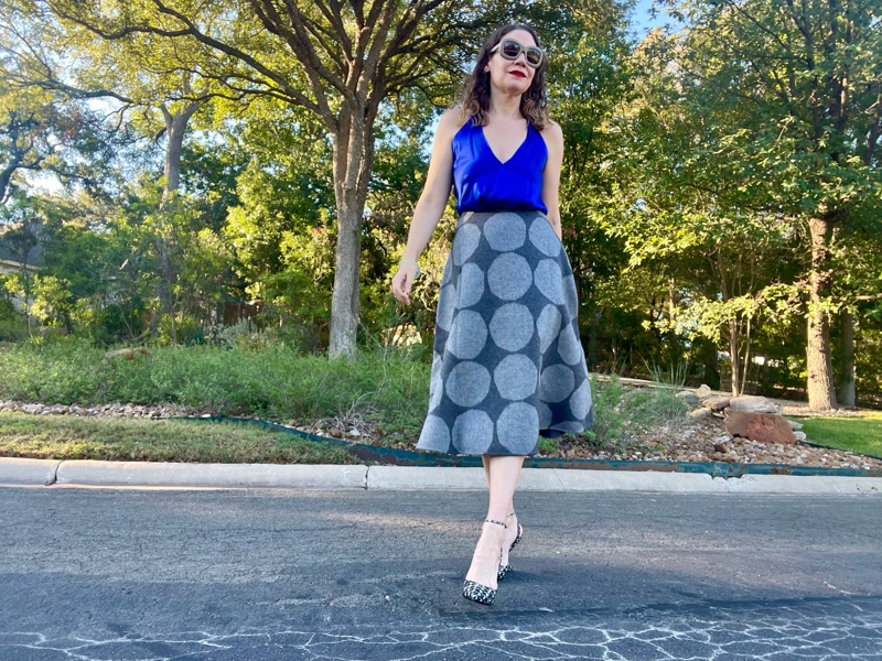 a woman in a blue silk halter top with a grey felt circle skirt with grey polka dots on it and houndstooth printed wedges