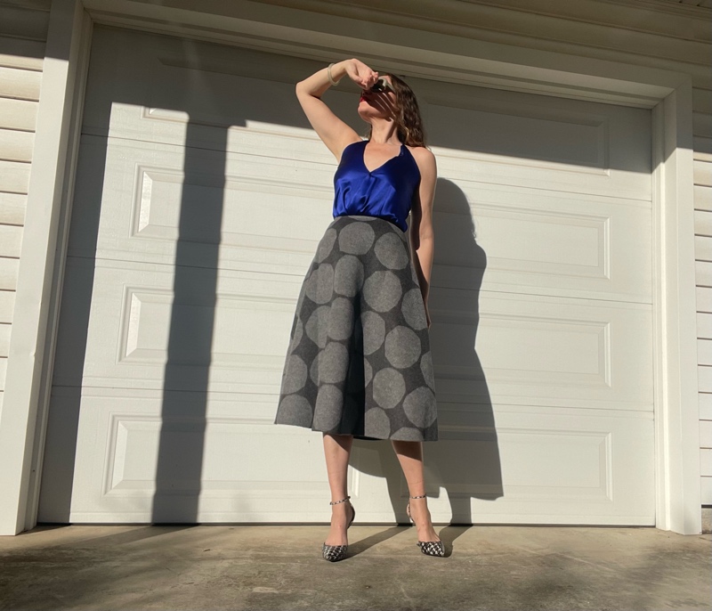 a woman in a blue silk halter top with a grey felt circle skirt with grey polka dots on it and houndstooth printed wedges
