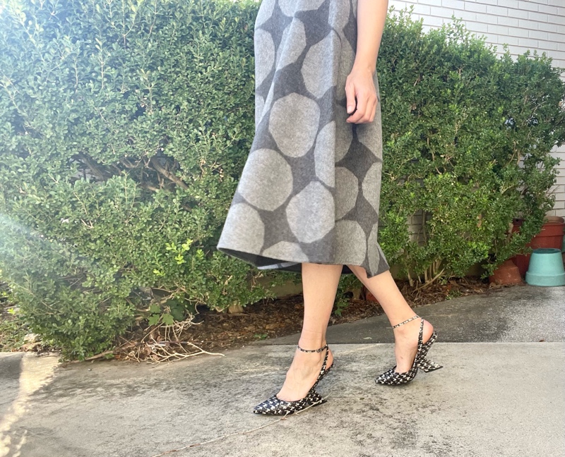 a woman in a blue silk halter top and a grey felt circle skirt with light grey polka dots and houndstooth printed wedges