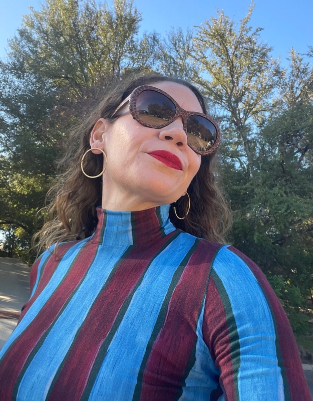 a woman in a blue and red striped skirt and turtleneck set with red fringe shoes and a leopard bag 