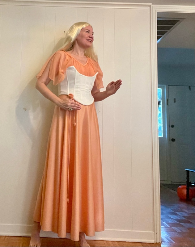 a woman in a peach dress with a white corset and a long, blonde wig