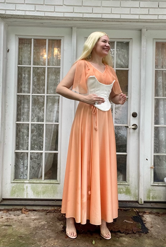 a woman in a peach dress and a white corset and a long blonde wig