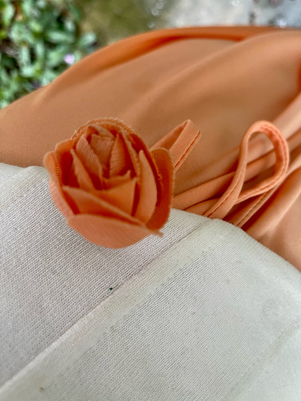  a woman in a peach dress with a white corset and flower detail 