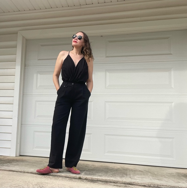 a woman in a black v neck with black trousers and pink mules