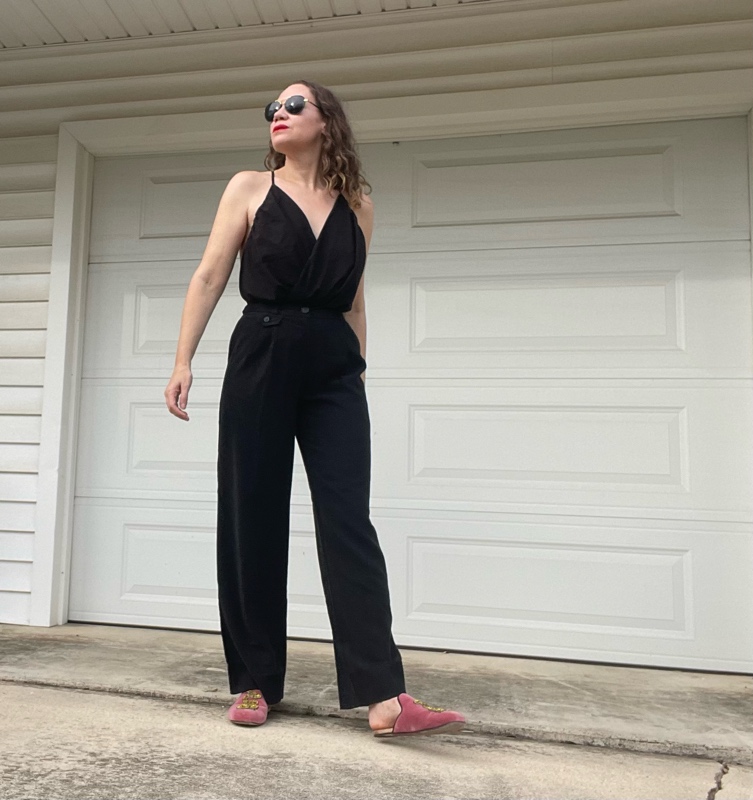 a woman in a black v neck and black trousers and pink mules