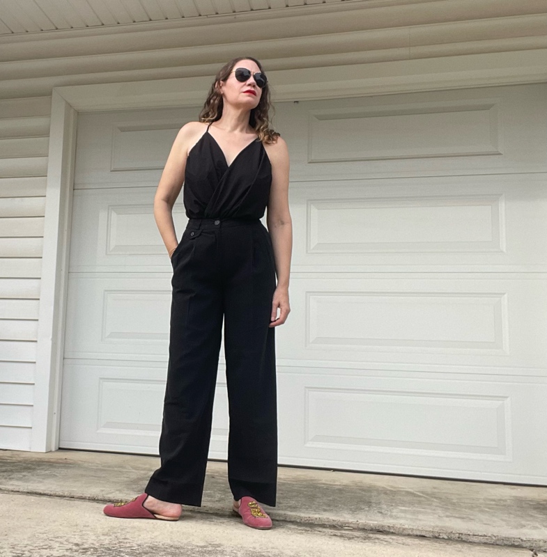 a woman in a black v neck with black trousers and pink mules