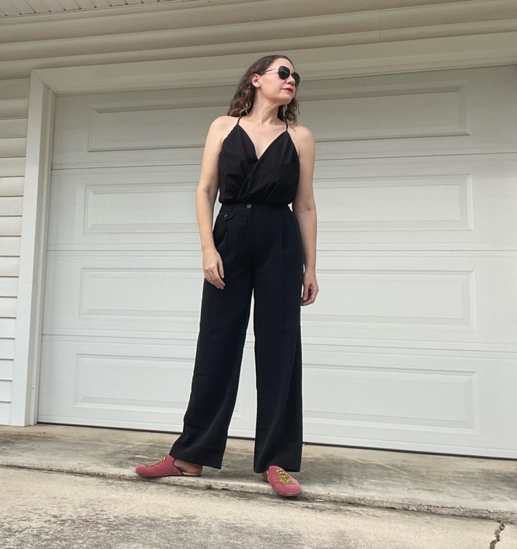 a woman in a black v neck with black trousers and pink mules