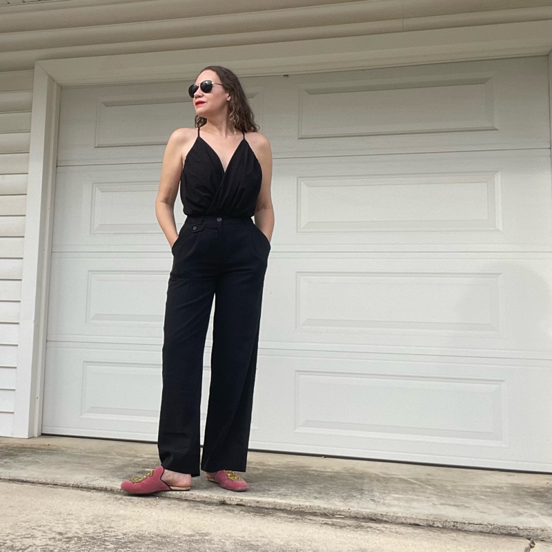 a woman in a v neck with black trousers and pink mules