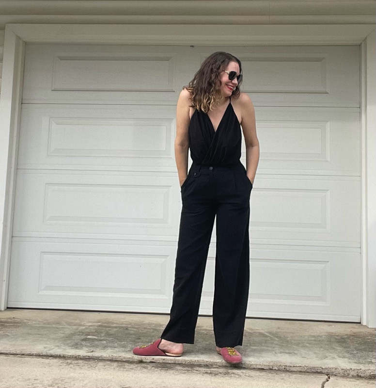 a woman in a black v neck and black trousers with pink mules