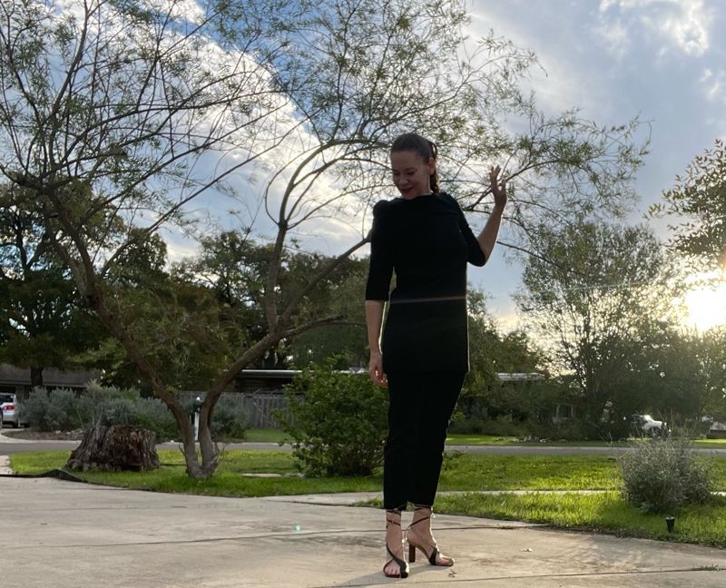  a woman in a black mini Dress over black cropped pants with asymmetrical black and tan heels 