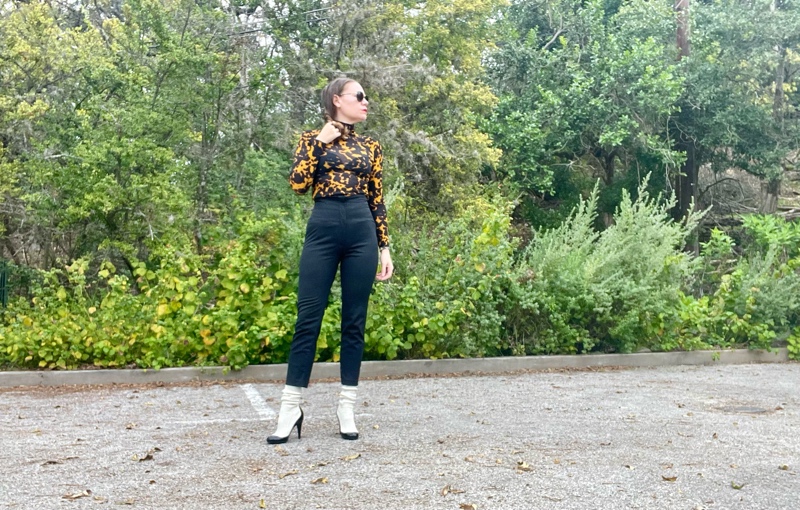 a woman in a tortoiseshell turtleneck, high waisted black pants, and white sock boots