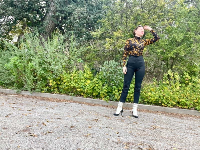 a woman in a tortoiseshell turtleneck, high waisted black pants and white sock boots
