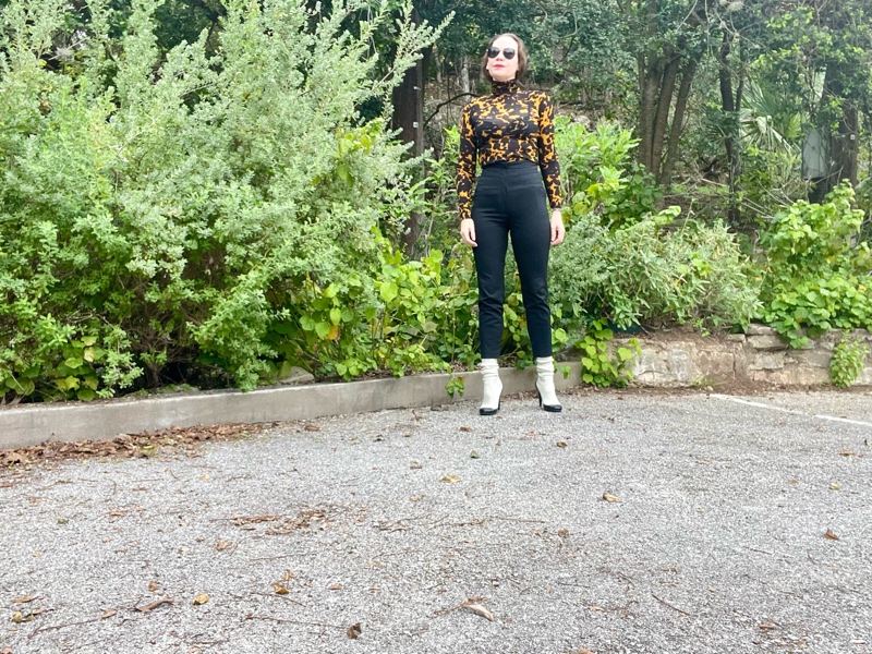 a woman in a tortoiseshell turtleneck with high waisted cropped black pants and white sock boots