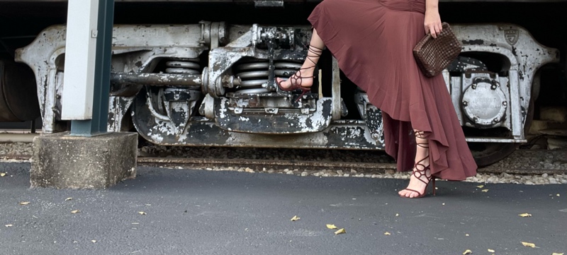 a close up of a brown lace up heel and dress on a train wheel