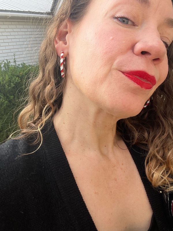 a close up of red and white enamel hoop earrings and red lips