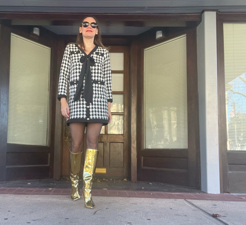 a woman in a mini houndstooth tweed dress  and gold wedge boots