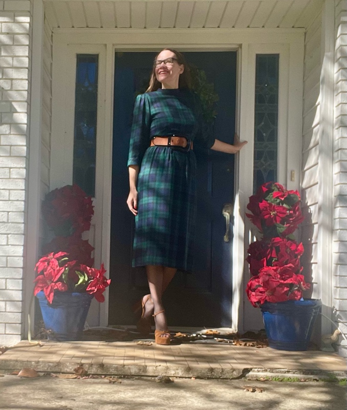 a woman in black watch plaid dress, brown belt, black hose and brown suede platforms 