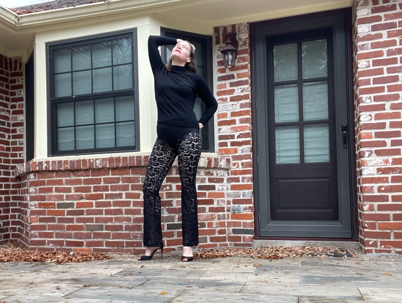 a woman in a black turtleneck, black sheer lace pants and black peep toe heels