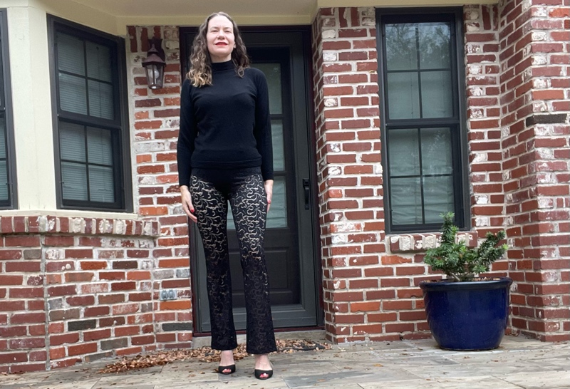 a woman in a black turtleneck and sheer black lace pants with black peep toe  shoes