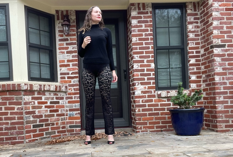 a woman in a black turtleneck and black sheer lace pants and black peep toe heels