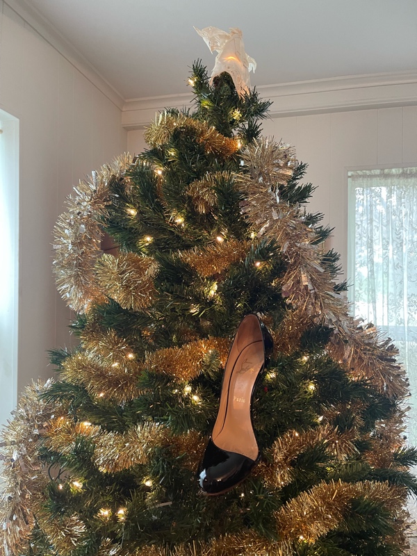 a black Louboutin heel hung as an ornament in a Christmas tree