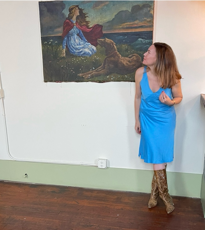 a woman in a blue slip dress, snakeskin boots, a tan coat and blue clutch