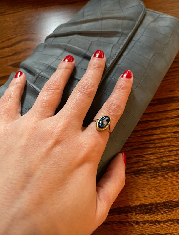 a woman with red nails, a blue cameo ring and a blue clutch