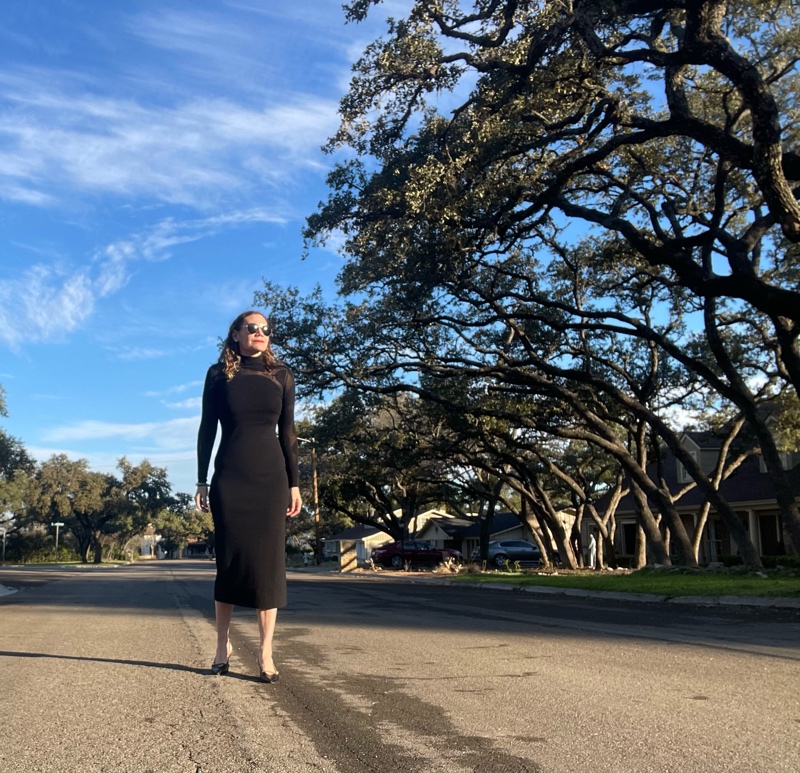 a woman in a body con dress with polka dots on sleeves and back with pearl earrings and shoes