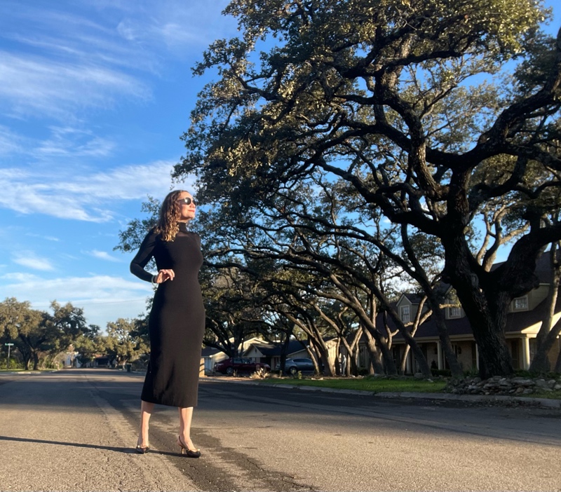 a woman in a black knit body con dress with polka dots on the sleeves and bacj