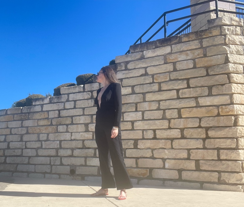 a woman in a black tux jumpsuit with red cage sandals 