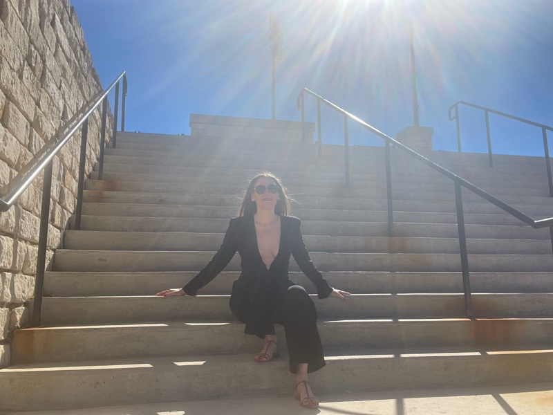 a woman in a black tux jumpsuit and red cage sandals