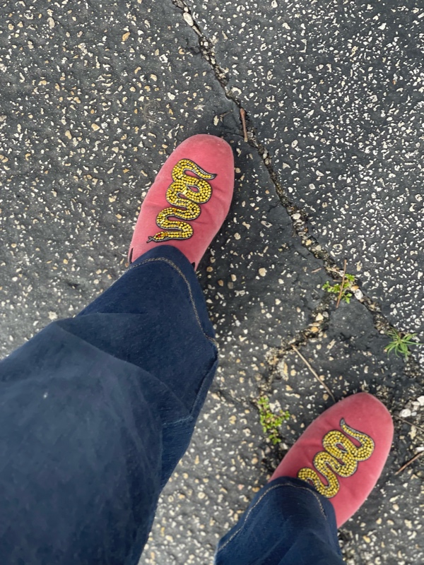 a close up of pink velvet mules with beaded snakes on them and jean cuffs