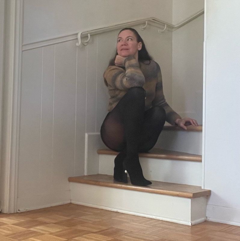 a woman in hose and short shorts with a striped cardigan and a boots with pearls on stairs 