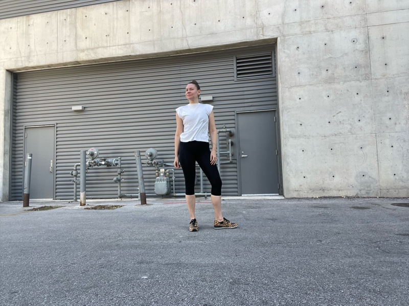 a woman in black workout capri leggings with leopard sneakers and a white tee 