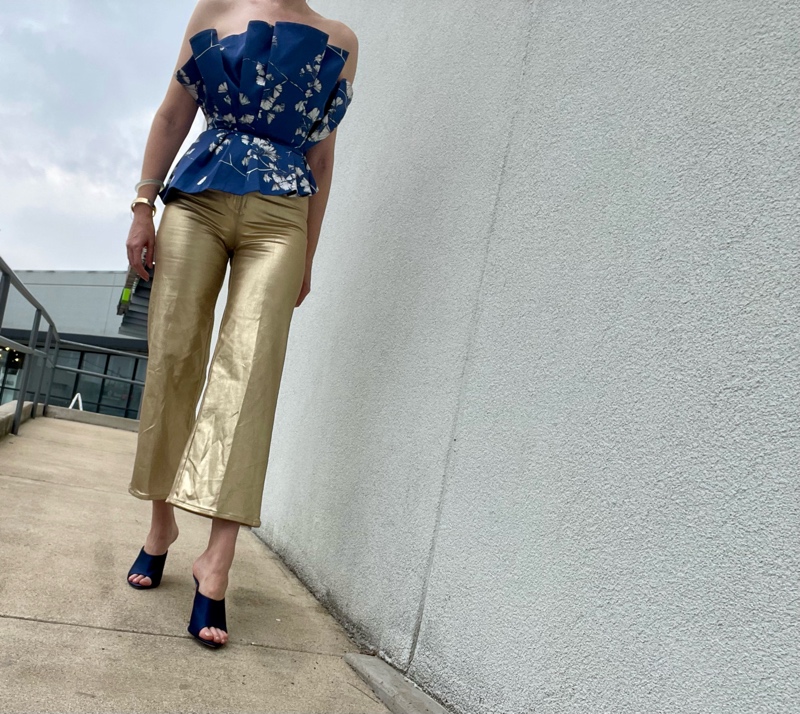 a woman in gold pants with a blue floral bustier and blue mules