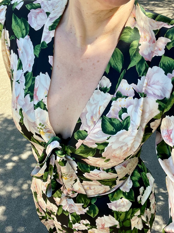 a woman in a green, black and pink rose printed skirt suit