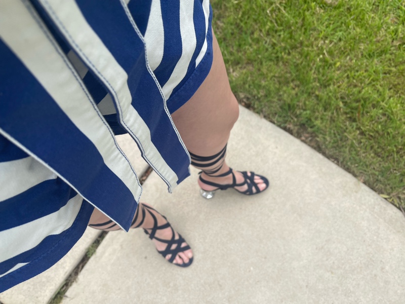 a woman in a blue and white striped romper with lace up navy suede sandals