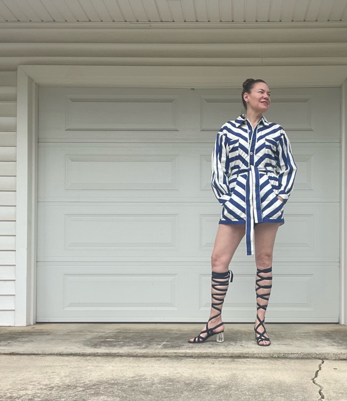 a woman in a blue and white striped romper with lace up navy suede sandals