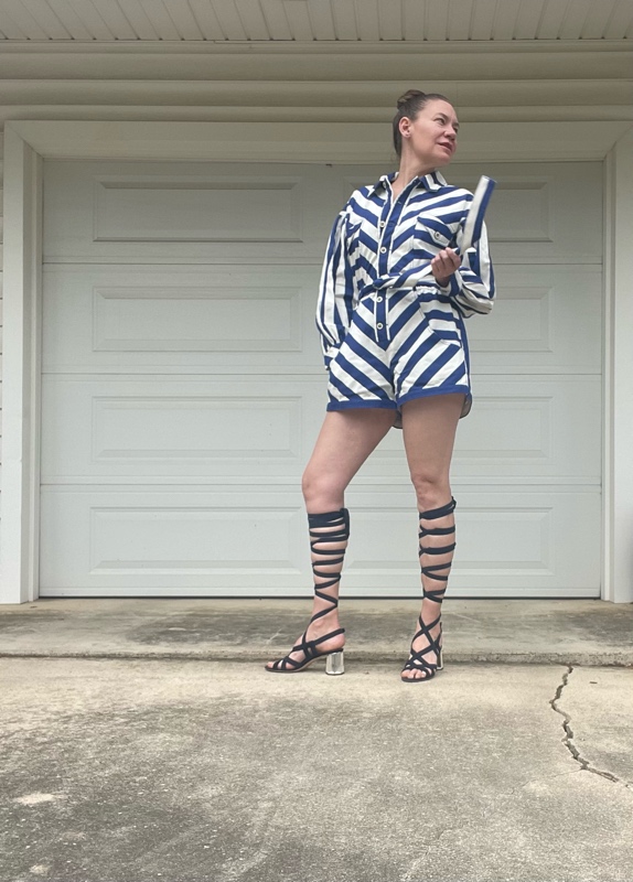 a woman in a blue and white striped romper with lace up navy suede sandals