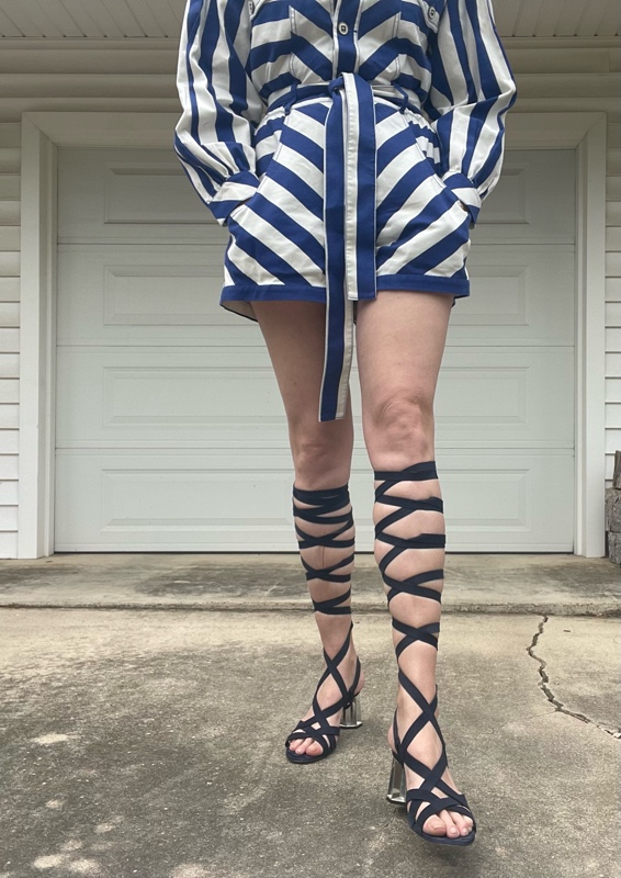 a woman in a blue and white striped romper with lace up navy suede sandals