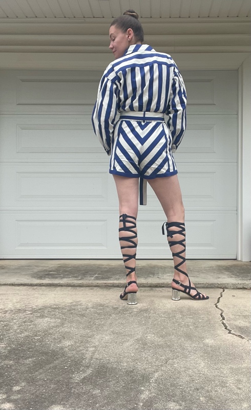 a woman in a blue and white striped romper with lace up navy suede sandals
