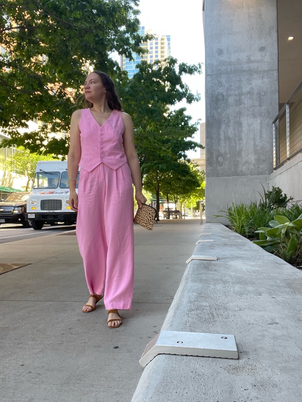 a woman in a pink linen vest and trousers with kitten heel sandals and a leopard clutch