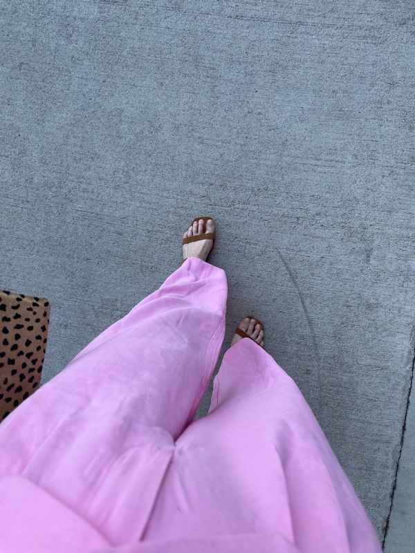 a woman in a pink linen vest and trousers with kitten heel sandals and a leopard clutch